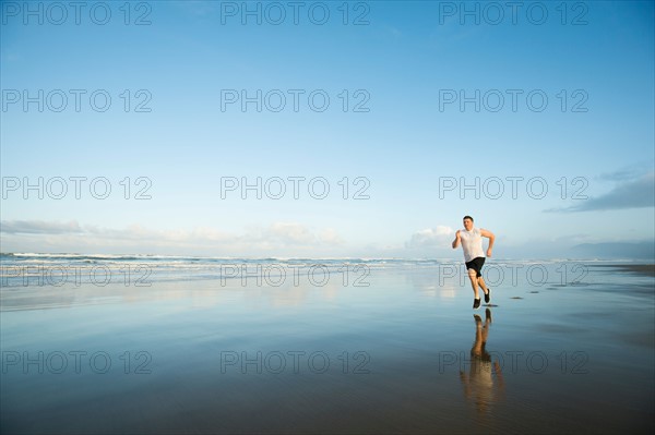 Young adult man running on beach