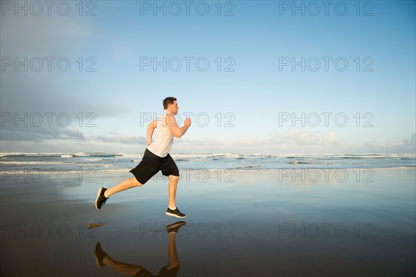 Young adult man running on beach