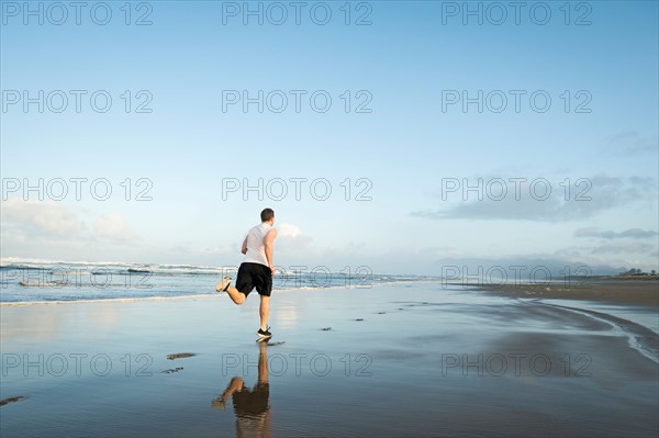 Young adult man running on beach