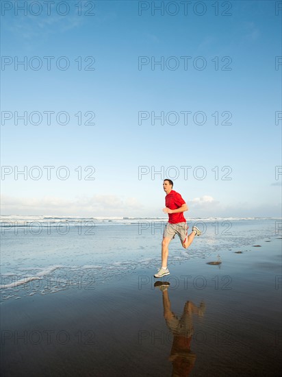 Young adult man running on beach