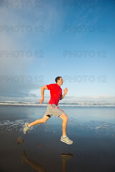 Young adult man running on beach