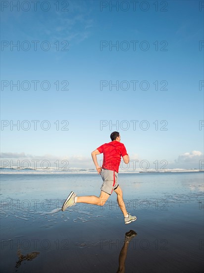 Young adult man running on beach