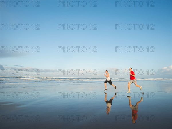 Young adult men running on beach