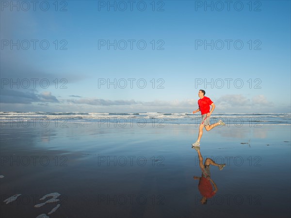 Young adult man running on beach