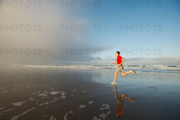 Young adult man running on beach