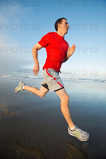 Young adult man running on beach