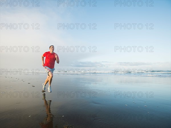 Young adult man running on beach