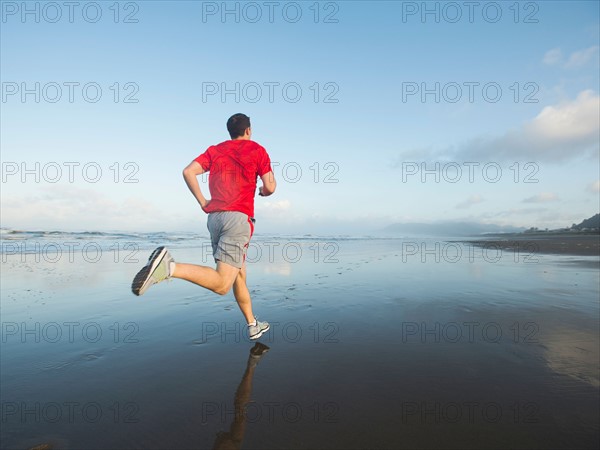 Young adult man running on beach