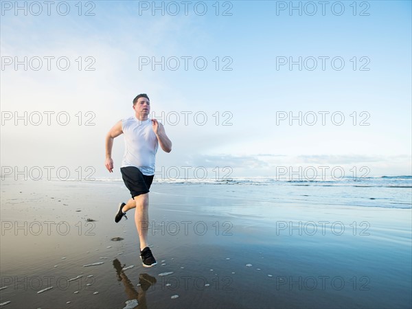 Young adult man running on beach