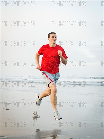 Young adult man running on beach