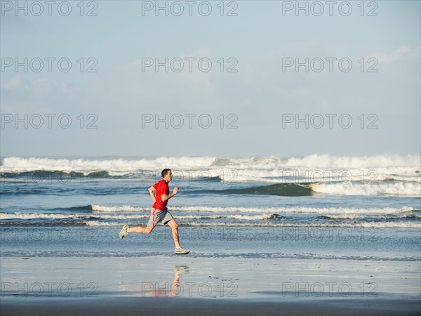 Young adult man running on beach