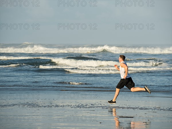 Young adult man running on beach