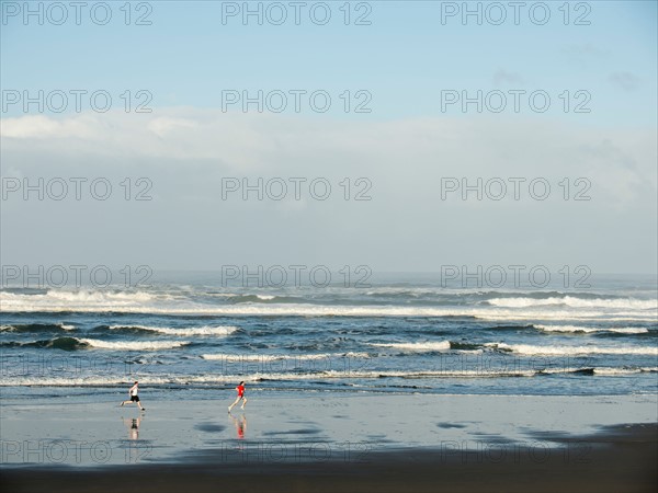 Young adult men running on beach