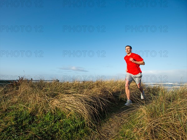 Young adult man running on dune