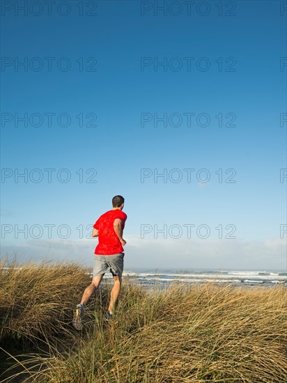 Young adult man running on dune