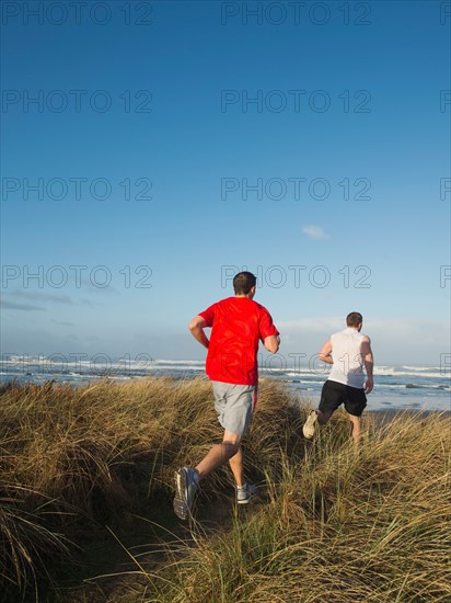 Young adult men running on dune