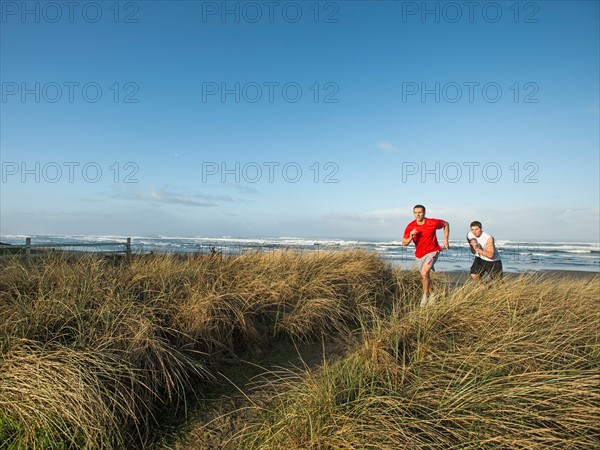 Young adult men running on dune