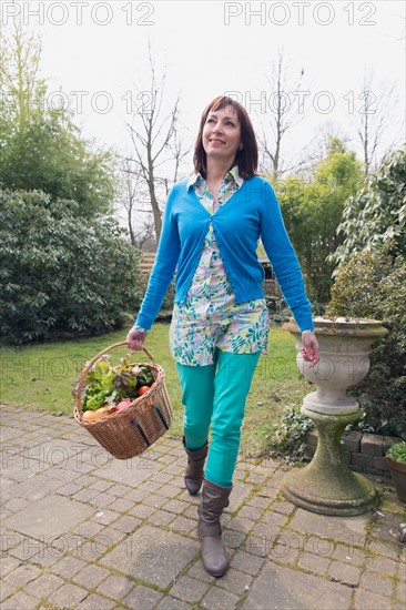 Mature woman with fresh vegetables in basket