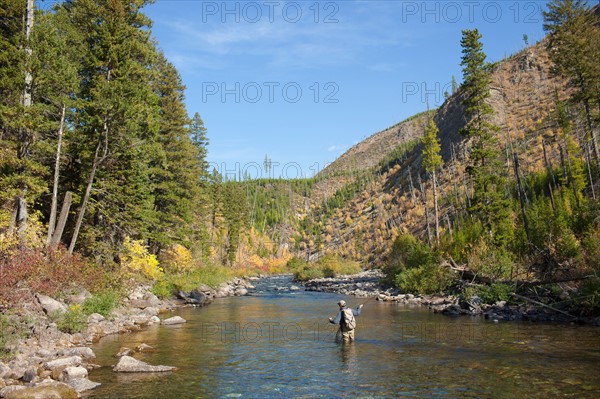 Fisherman wading in river