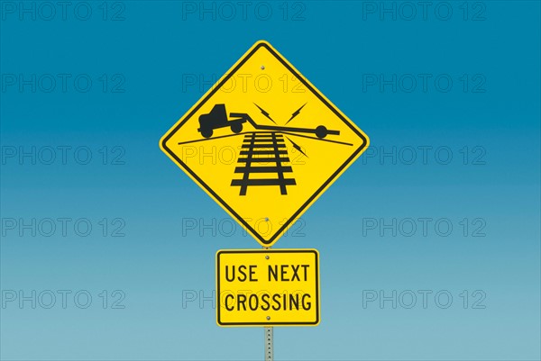 Yellow road sign depicting truck on railroad crossing