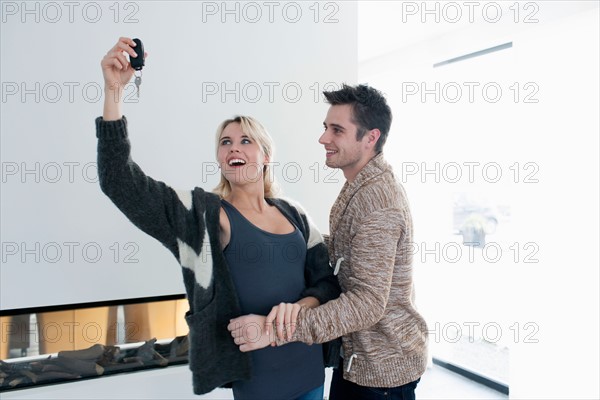 Woman holding car keys while man embracing her