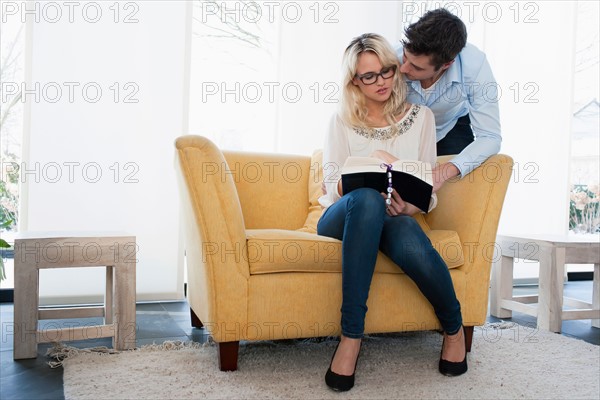 Woman reading book while man kissing her