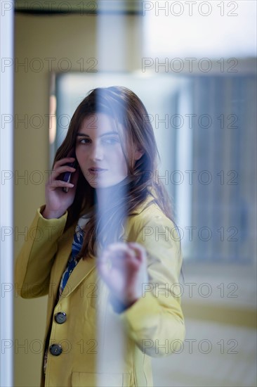 Woman behind glass door and talking on cell phone