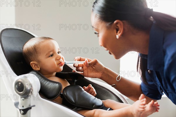 Mother giving medicine to baby (2-5 moths)