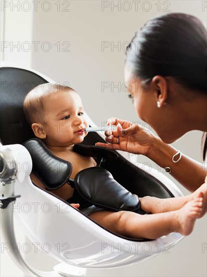 Mother giving medicine to baby (2-5 moths)