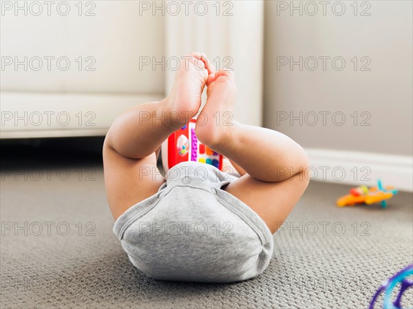 Baby boy (2-5 months) lying on floor playing