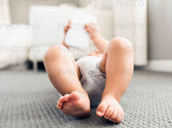 Baby boy (2-5 months) lying on floor playing