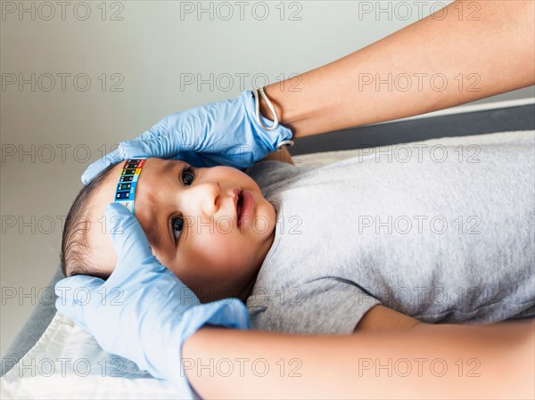 Nurse taking baby boy's (2-5 months) temperature