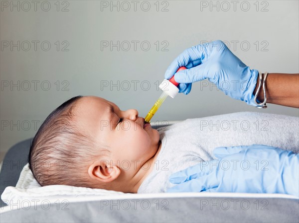 Nurse giving baby boy's (2-5 months) medicine using pipette