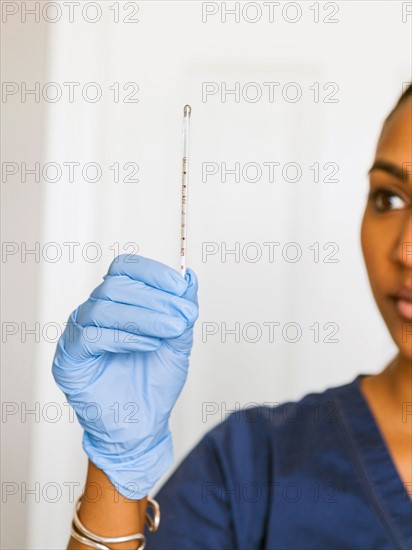 Female nurse looking at thermometer