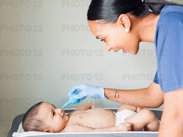 Nurse cleaning baby boy's (2-5 months) nose