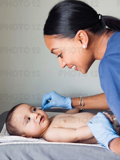 Nurse cleaning baby boy's (2-5 months) ear