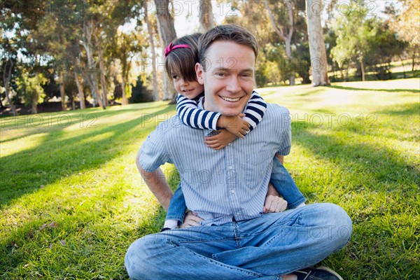 Daughter (4-5 years) embracing her father in park