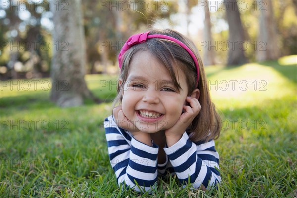 Portrait of smiling girl (4-5 years) lying on grass in park