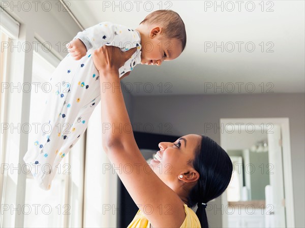 Woman holding up her baby son (2-5 months)