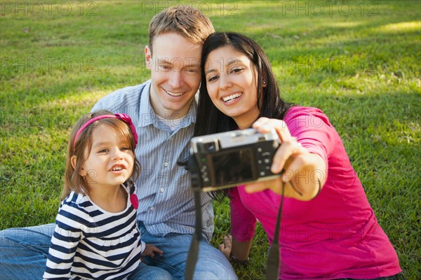 Family with daughter (4-5) playing in park and photographing themselves