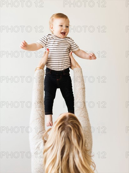 Mother holding up her daughter (12-17 months)