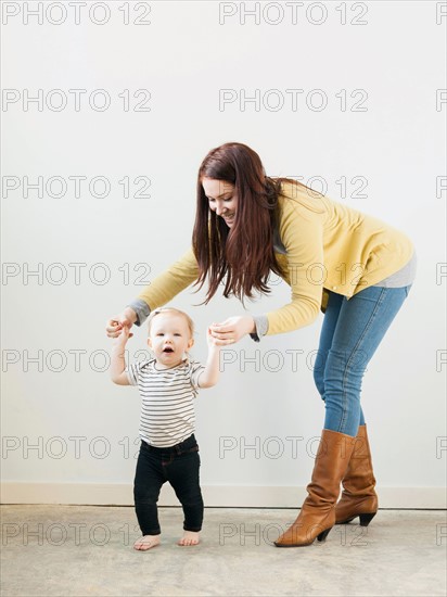 Baby girl (12-17 months) walking while mother assisting her