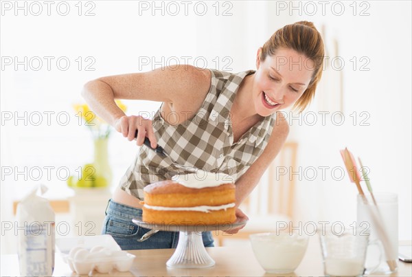 Woman decorating cake in kitchen.