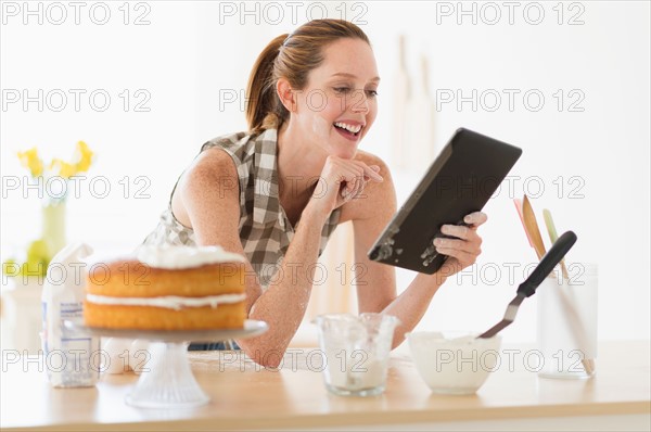 Woman using tablet pc in kitchen.