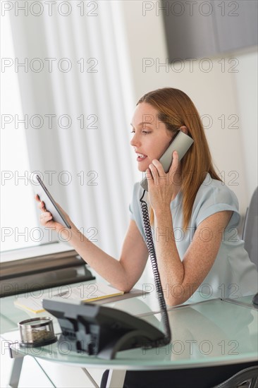 Business woman using phone and tablet pc in office.