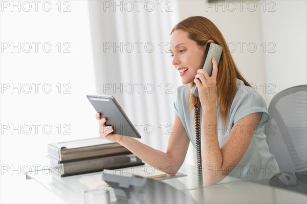 Business woman using phone and tablet pc in office.