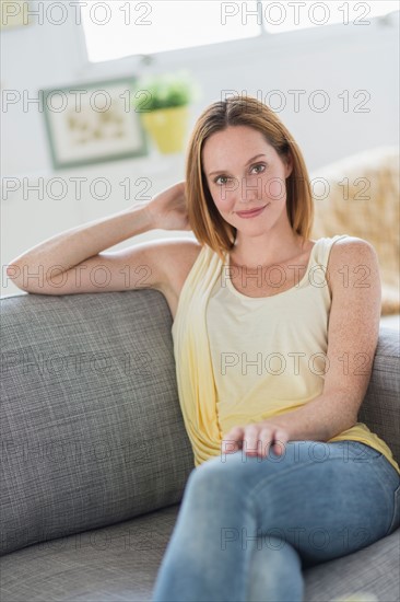 Portrait of young woman relaxing on sofa.
