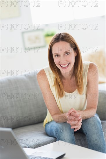 Portrait of young woman sitting on sofa.