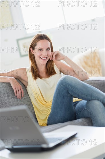 Portrait of young woman relaxing on sofa.