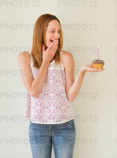 Woman holding birthday cupcake.